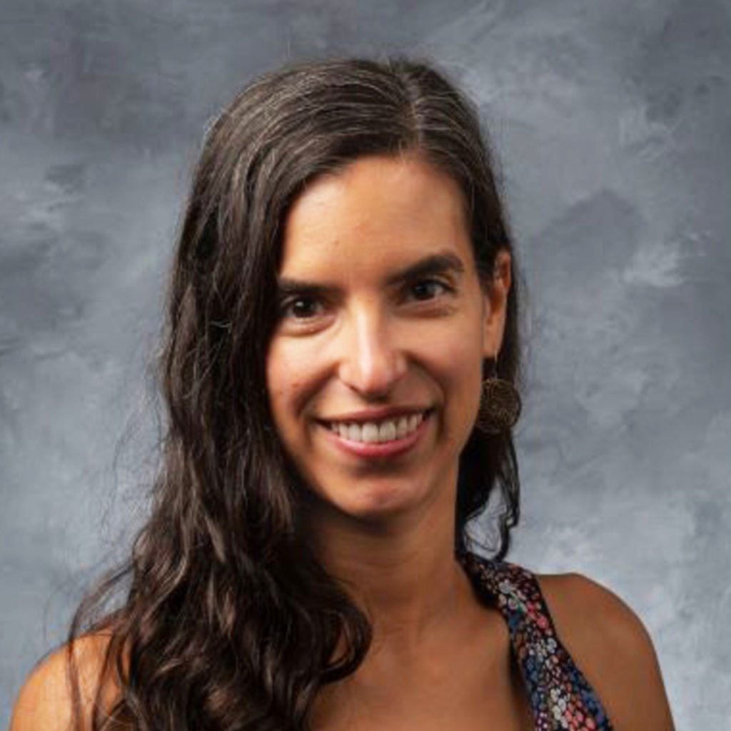 Christine sits in front of a blue gray background.