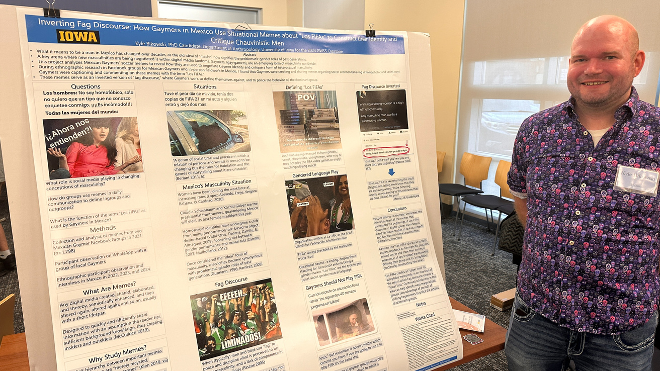 student stands in front of their poster presentation